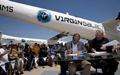 維珍集團創辦人理查‧布蘭森及 Aabar 總裁 Mohamed Badawy Al-Husseiny- 於美國威斯康辛州奧什科什舉行的航空展中進行簽約儀式，是次航空展更是維珍銀河的太空母船首次在奧什科什進行公開飛行示範表演